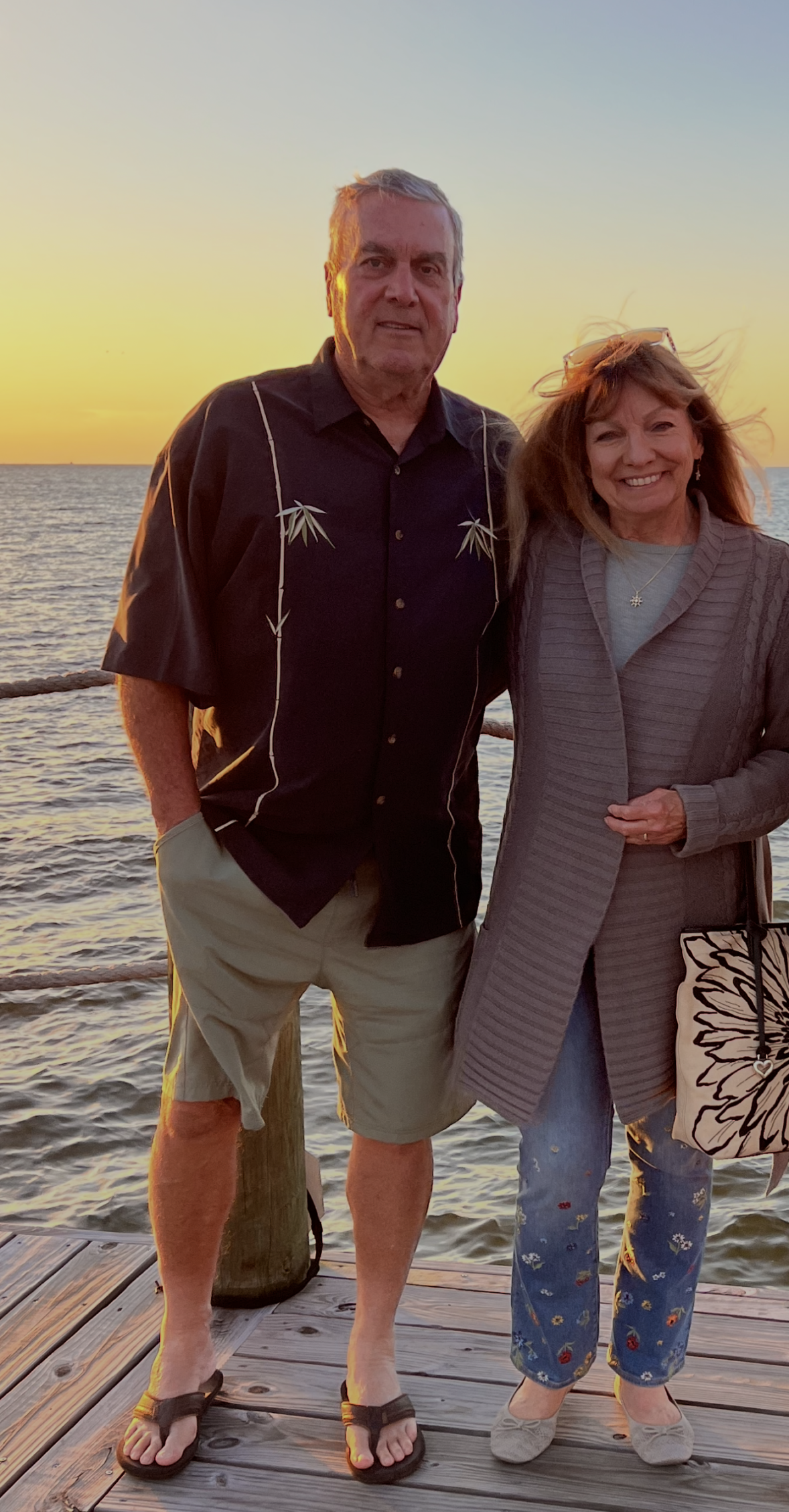 Carol Junge, Senior Mortgage Consultant with Better Way Home Loans, standing with her husband at sunset by the water